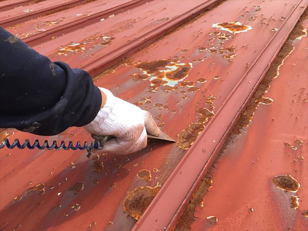 金属屋根のケレン作業をおこなっていきます。  錆による腐食が激しい箇所はスクレーパーを使って一気に除去していきます。