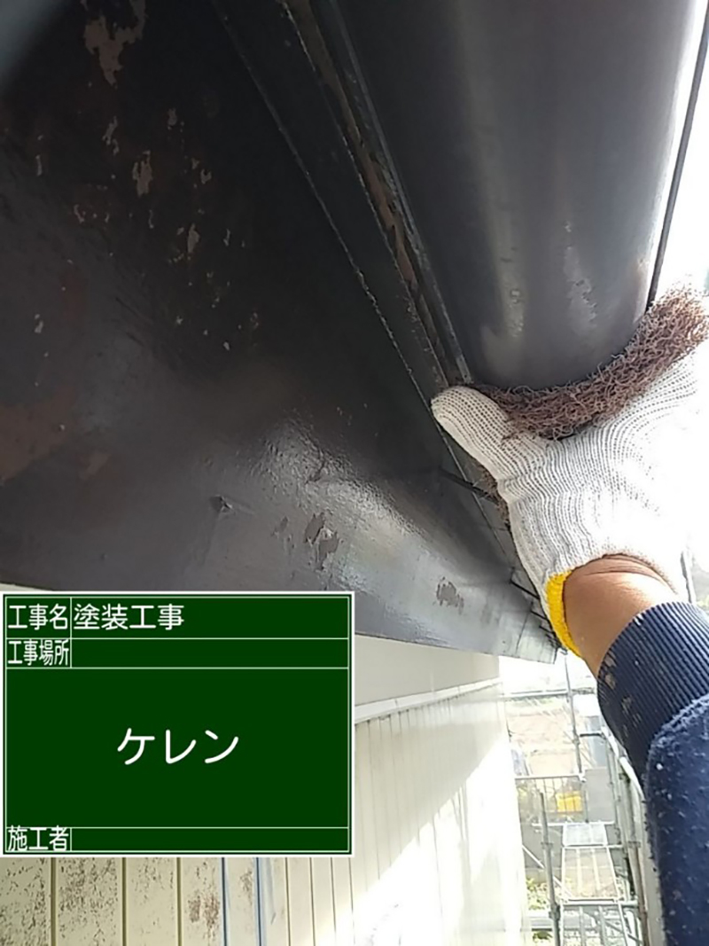 軍手をはめた手が雨樋を研磨している