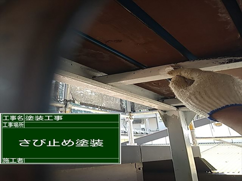 刷毛を持つ手で白く塗られていく鉄骨
