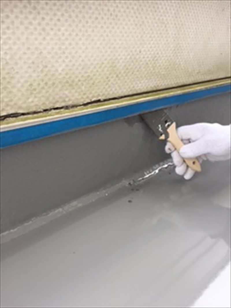 ベランダに防水材を塗布しています。  ハケを使い、細かい所まで丁寧に  防水材を押し込んでいます。