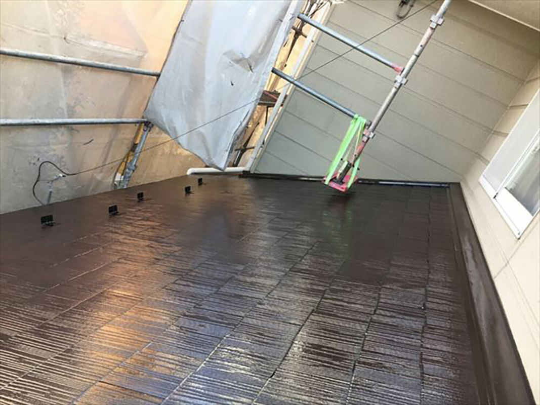 二階の屋根（下屋根）にも下塗りを行います。  屋根塗装の際、屋根板と屋根板の隙間部分はローラーだけだと塗り残しができたり、逆に溜めができてしまうほど塗料を乗せてしまう場合があります。  その場合は、先に刷毛で屋根の隙間部分だけを塗装し、その後ローラーで屋根塗装をしていきます。  そうすることで、隙間部分の塗布量も一定にすることができます。  刷毛で細かな部分を塗装することをダメ込みと呼びます。