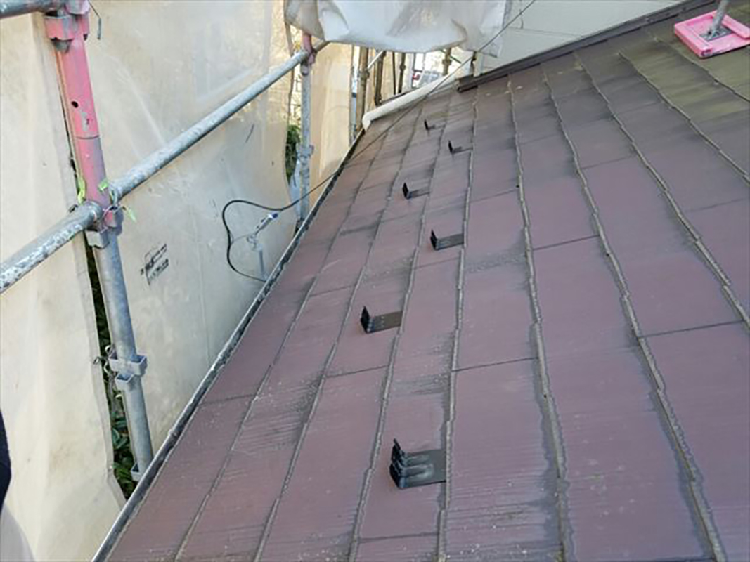 屋根塗装の前に取り付けていきます。  屋根板と屋根板の間に、タスペーサーを簡単に挟んでおきます。  タスペーサーは屋根板１枚につき２つを両端よりやや内側に取り付けます。２つ取り付けることにより、屋根板を平行にさせ全体の隙間を一定にします。