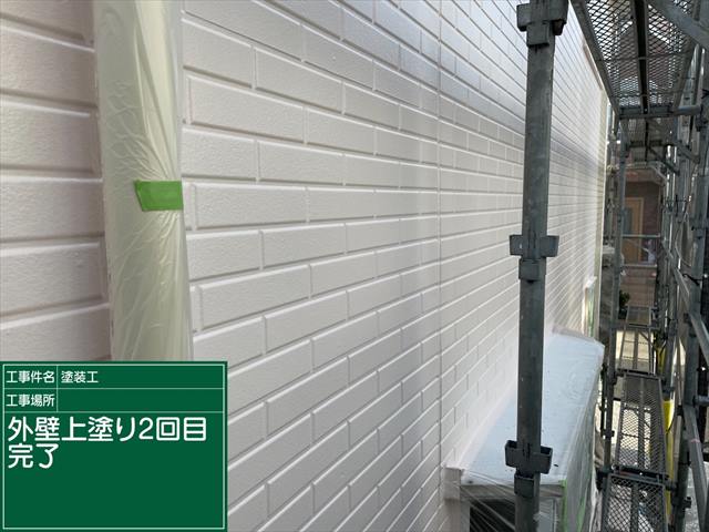 手前に養生された雨樋、足場がみえる外壁