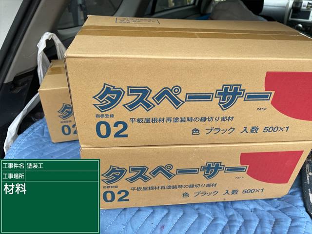 車に積まれたダンボールには「タスペーサー、平板屋根材再塗装時の縁切り部材」と書かれている